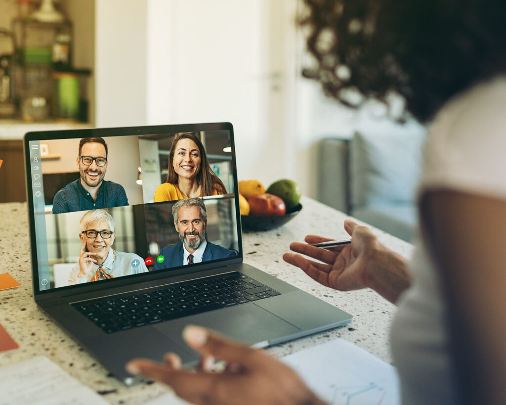 Woman with laptop looking at colleagues on screen during a web conference